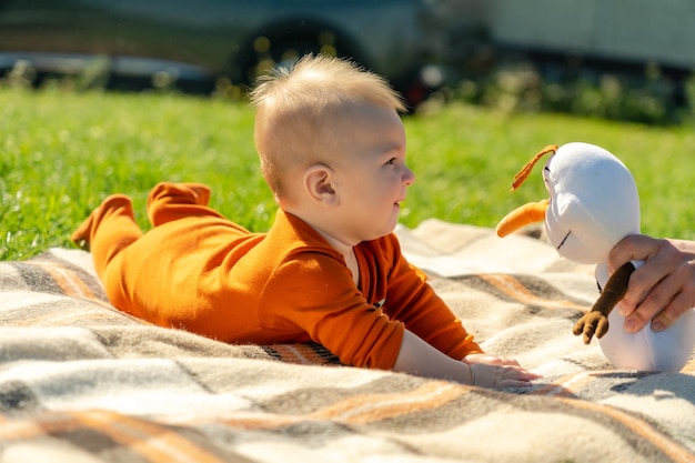 Smiling baby lying on the blanket on summer grass