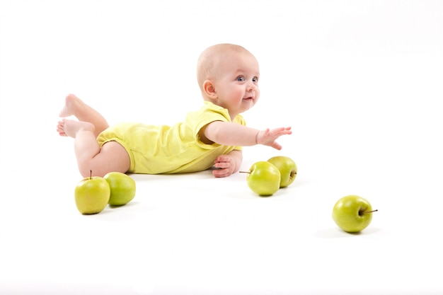 Smiling baby lying on the ground to include apples