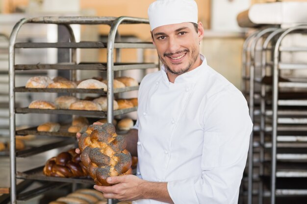 Smiling baker holding fresh loaf