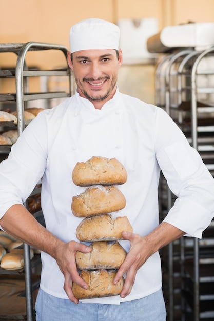 Smiling baker holding fresh loaves