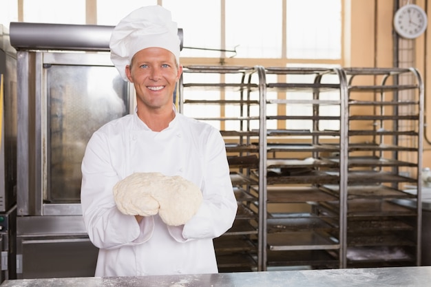 Smiling baker holding raw dough