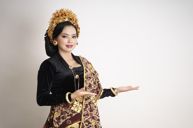 Smiling balinese woman wearing traditional clothes with hand gestures presenting