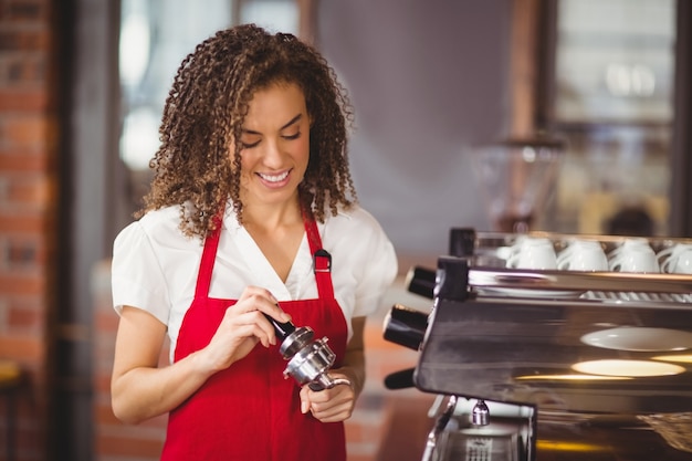 A smiling barista pressing coffee