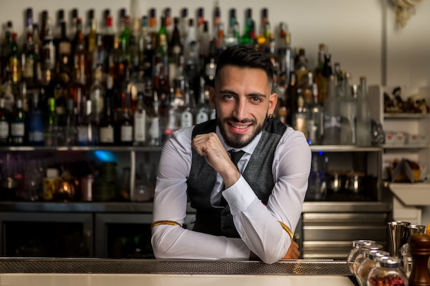 Smiling barman standing at bar counter