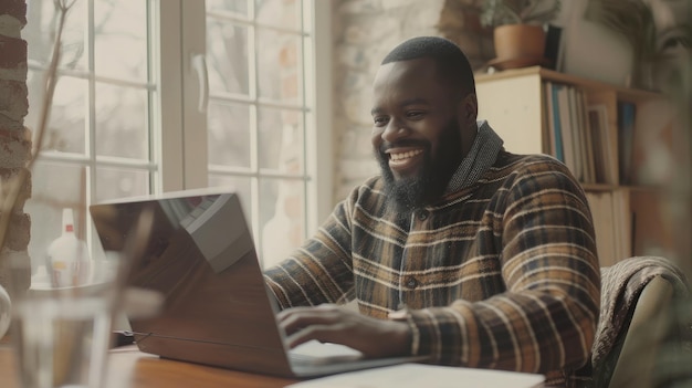 Smiling bearded African man using laptop at home while sitting the wooden tableMale hands typing on the notebook keyboardConcept of young people work mobile devicesBlurred window backgroundwide