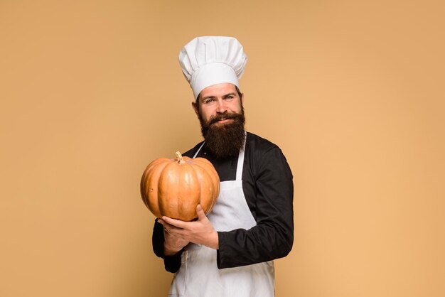 カボチャの感謝祭の日料理ハロウィーン料理秋の作物と季節のひげを生やしたシェフの笑顔