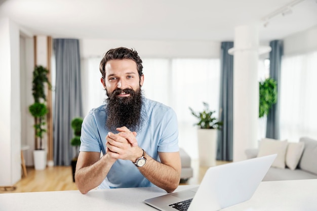 A smiling bearded man at his cozy home looking at the camera