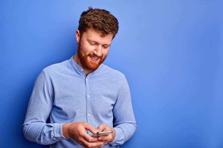 Photo smiling bearded man is chatting with someone on smartphone