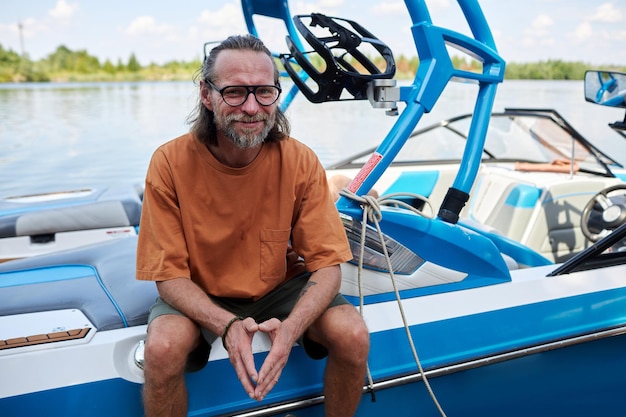 Smiling bearded man sitting on boat water sports outdoors