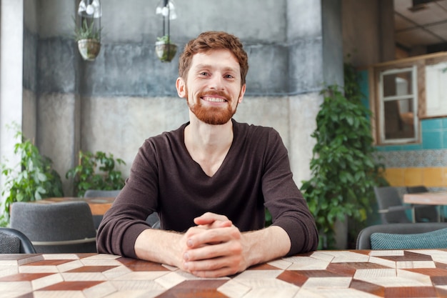 Smiling bearded man at table in cafe