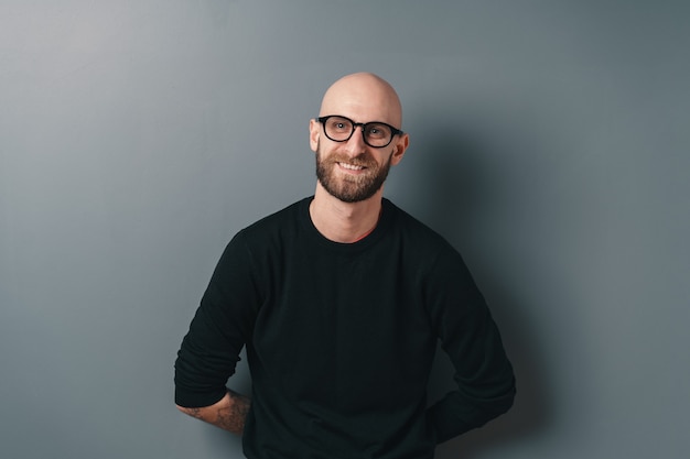 Smiling bearded young man on gray