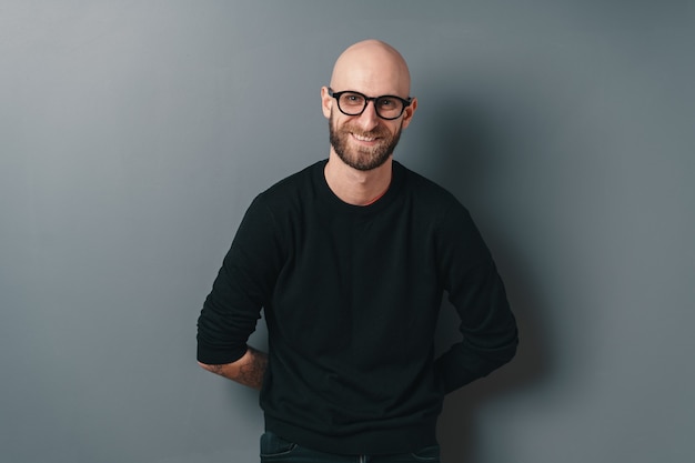 Smiling bearded young man on gray