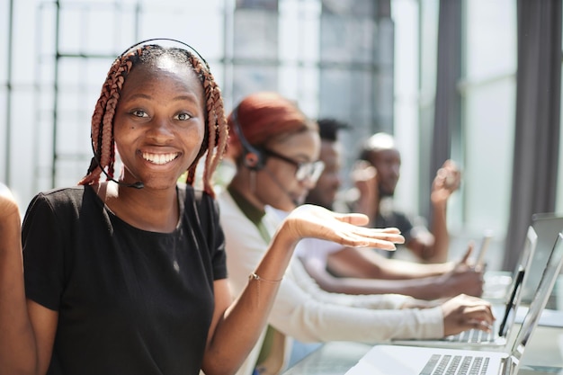 Smiling beautiful African American woman working in call center with diverse team