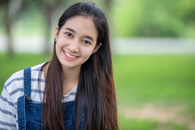 La bella ragazza asiatica sorridente all'albero sul parco di estate per si rilassa il tempo