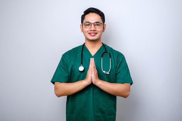 Smiling beautiful asian male doctor physician in scrubs smiling greeting gesture isolated white background