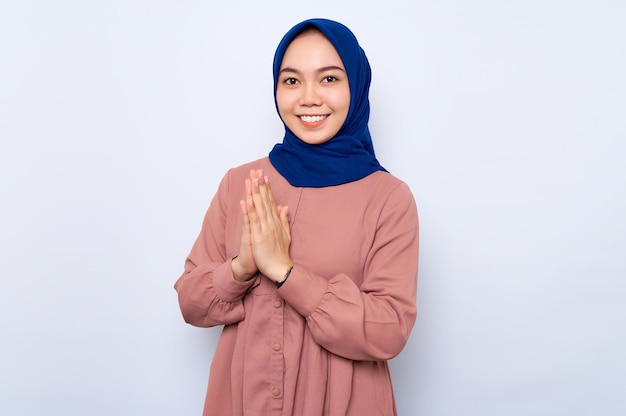 Smiling beautiful Asian muslim woman in casual shirt gesturing eid mubarak greeting isolated over white background People religious lifestyle concept