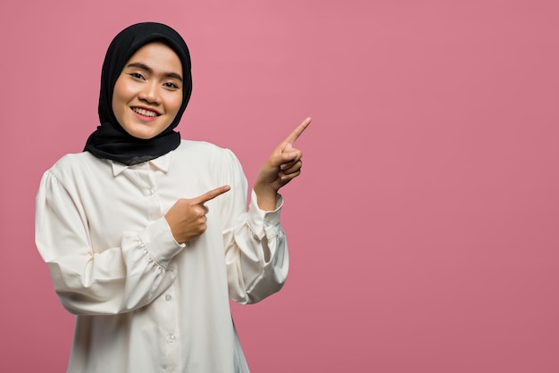 Smiling beautiful Asian woman pointing to empty space