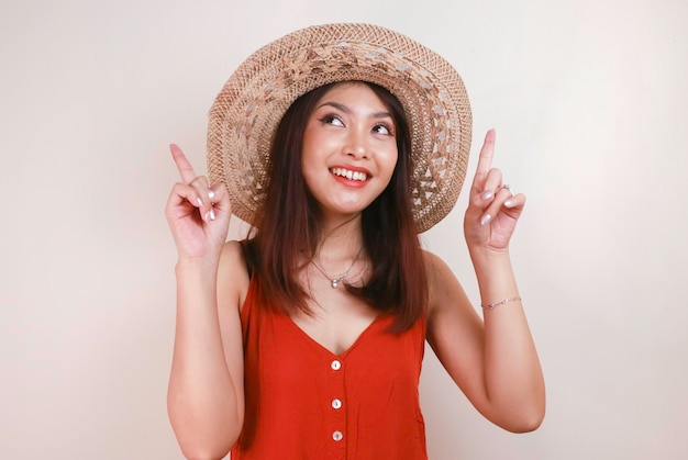 Smiling beautiful Asian woman pointing finger upward to empty space in studio white isolated background