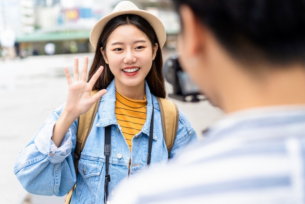 La bella donna asiatica sorridente dice ciao gesto con la mano