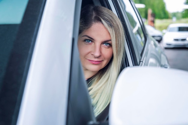 白い車を運転する笑顔の美しい金の女性 旅行とアクティブなライフスタイル クローズアップ