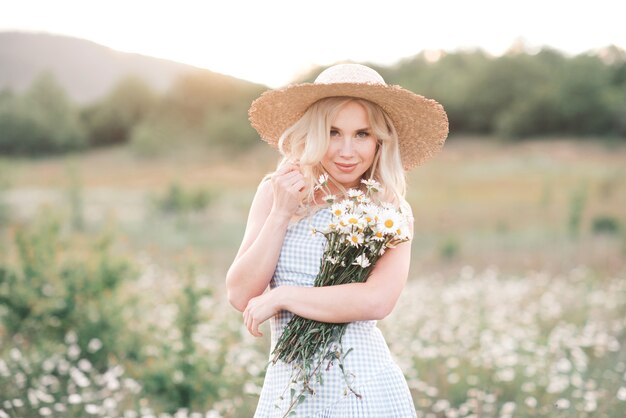 Smiling beautiful blonde woman holding bouquet of fresh daisy