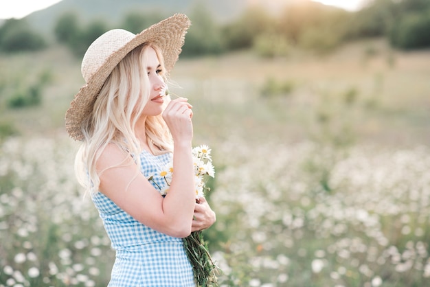 Smiling beautiful blonde woman holding bouquet of fresh daisy