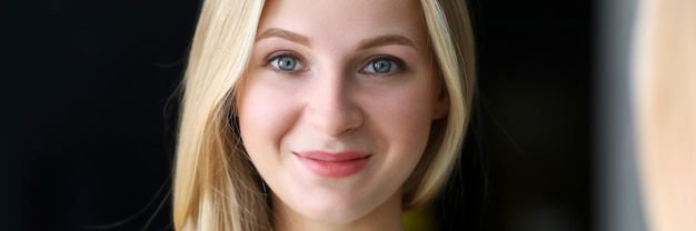 Smiling beautiful blonde woman looking in mirror