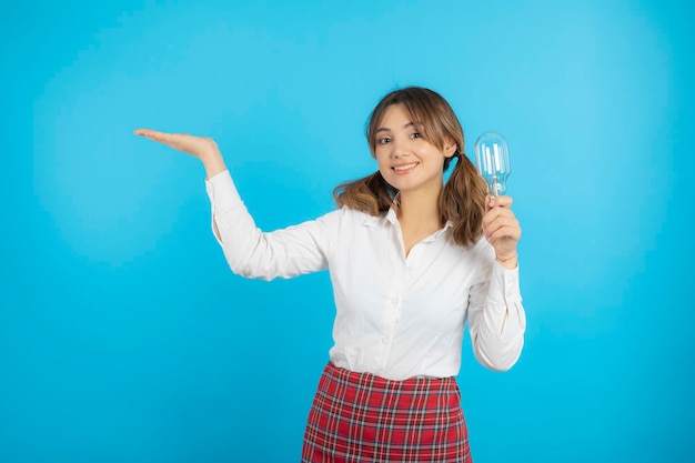 写真 アイデア電球を持って笑顔の美しい女子大生と彼女の手を右側に上げます。高品質の写真