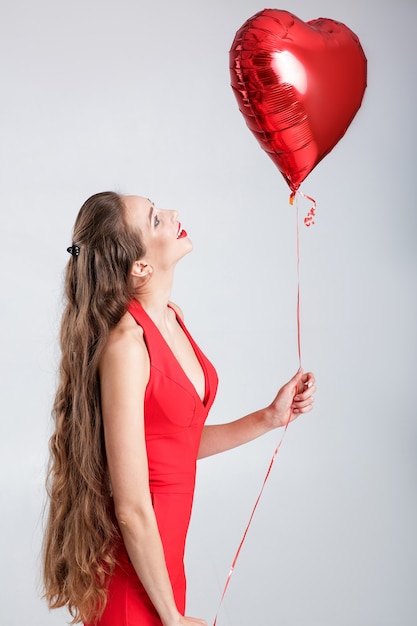 Foto sorridente bella donna riccia con palloncini d'aria a forma di cuore per il giorno di san valentino