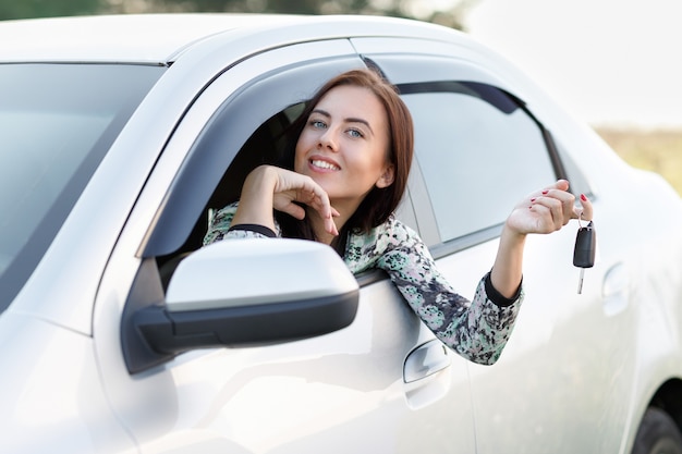 Smiling beautiful girl in the car holds the keys