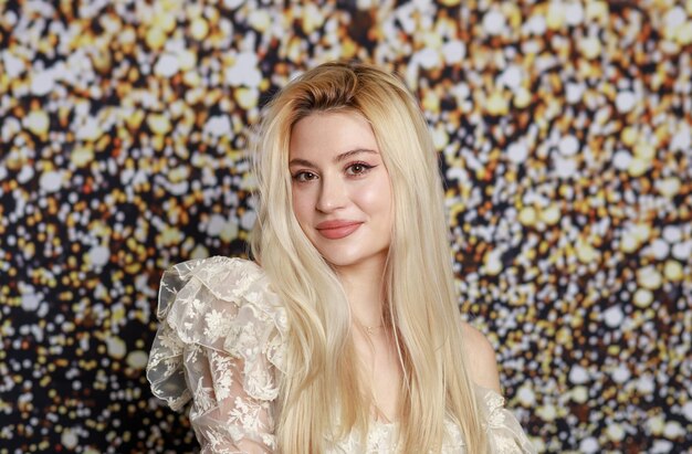 smiling beautiful lady standing on gilded background and looking at the camera