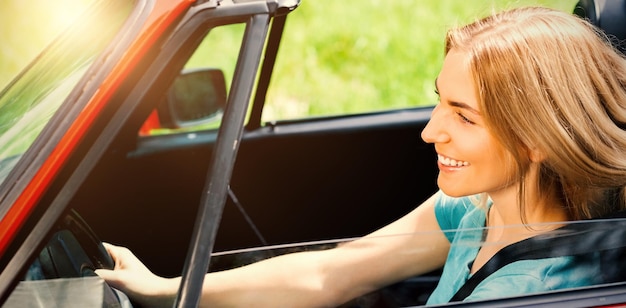 晴れた日に赤いカブリオレを運転して笑顔の美しい女性