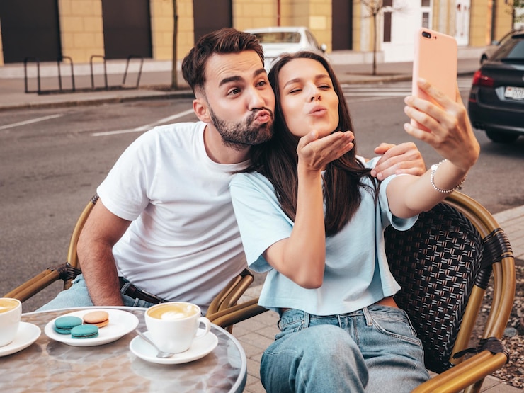 Фотография улыбающаяся красивая женщина и ее симпатичный парень пьют чай и кофе в кафе на веранде на открытом воздухе