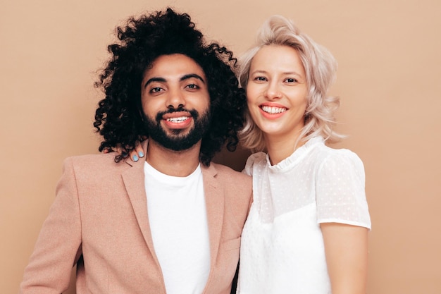 Foto bella donna sorridente e il suo bel ragazzo famiglia multirazziale allegra sexy che ha momenti teneri su sfondo beige in studio modelli multietnici che si abbracciano abbracciandosi l'un l'altroconcetto di amore