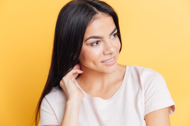 Bella donna sorridente che distoglie lo sguardo oltre il muro giallo