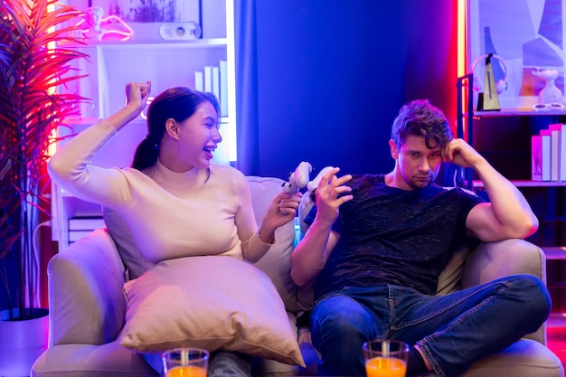 smiling beautiful woman winner on video game beside man loser postulate
