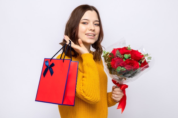 Smiling beautiful young girl holding gift bag with bouquet