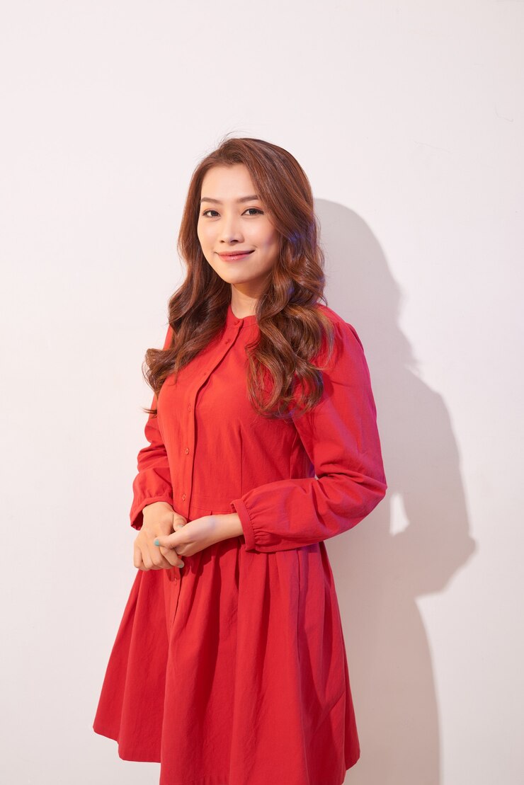 Photo 우아한 빨간 드레스에 웃는 아름 다운 젊은 여자 포즈
