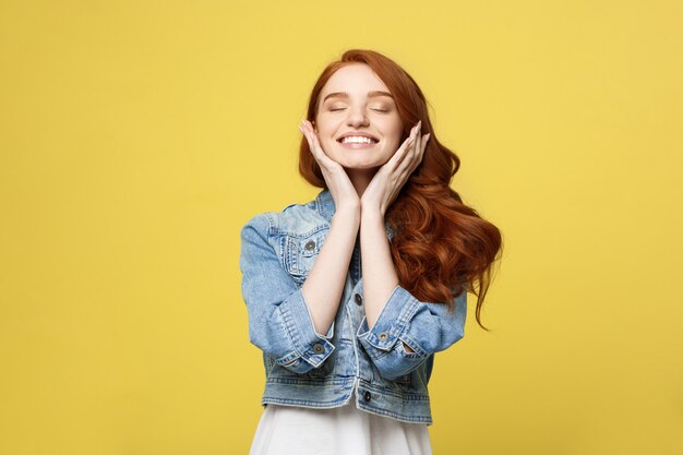 Smiling beautiful young woman in jean clothes posing with hands on chin.