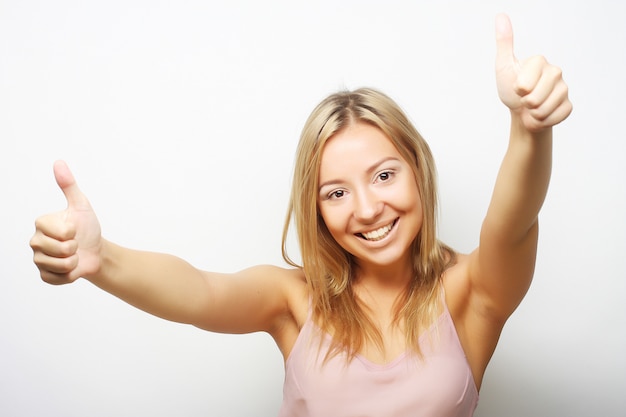 Smiling beautiful young woman showing thumbs up gesture