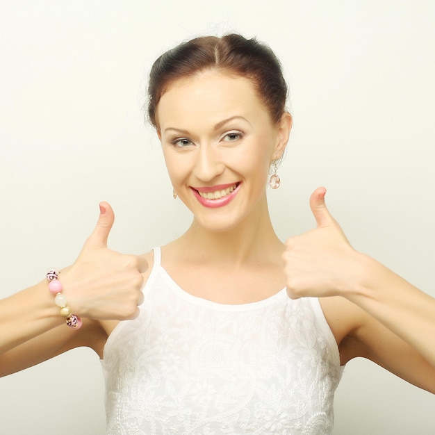 Smiling beautiful young woman showing thumbs up gesture