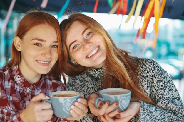 Улыбающиеся красивые молодые женщины позируют с кофе