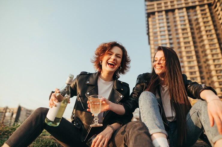 Photo smiling best friends girls drink wine on a walk