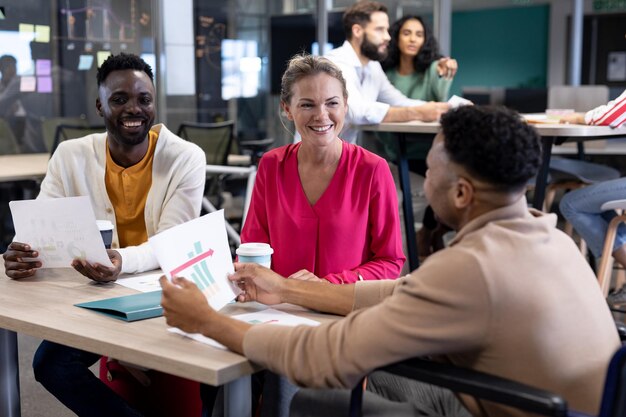 Smiling biracial colleagues discussing over document together in meeting at modern workplace