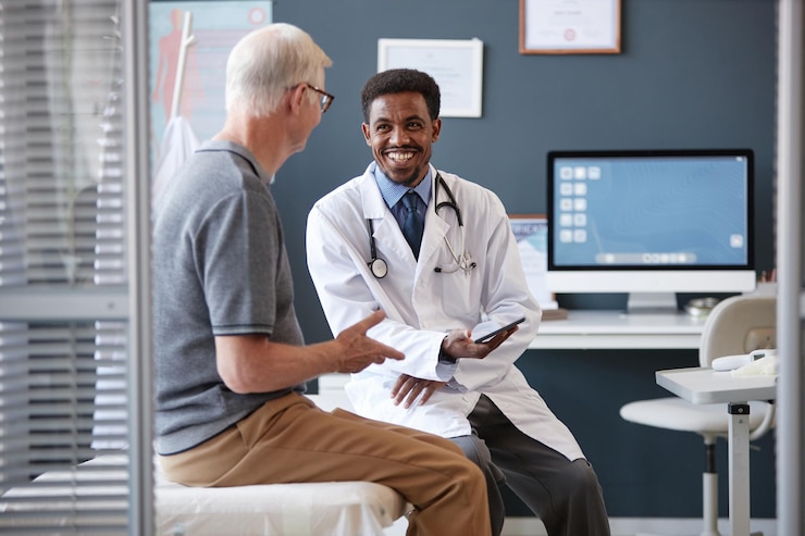 Photo smiling black doctor holding tablet talking to senior patient in consultation