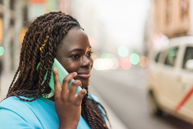 Smiling black girl talking on mobile in the city.