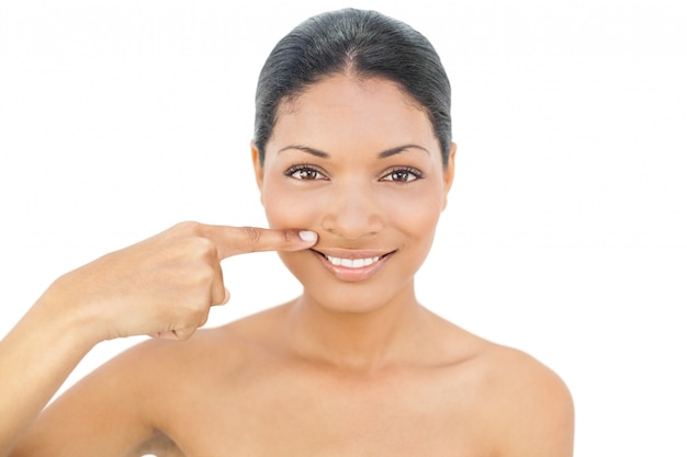 Smiling black haired model pointing above her lips