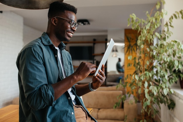 Smiling black man busy browsing tablet