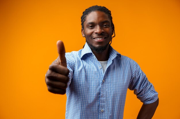 Smiling black man giving ok sign isolated on yellow background