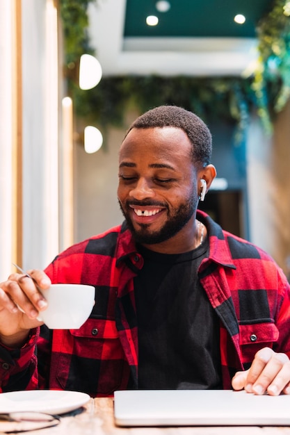 Smiling black man with cup of coffee in cafe
